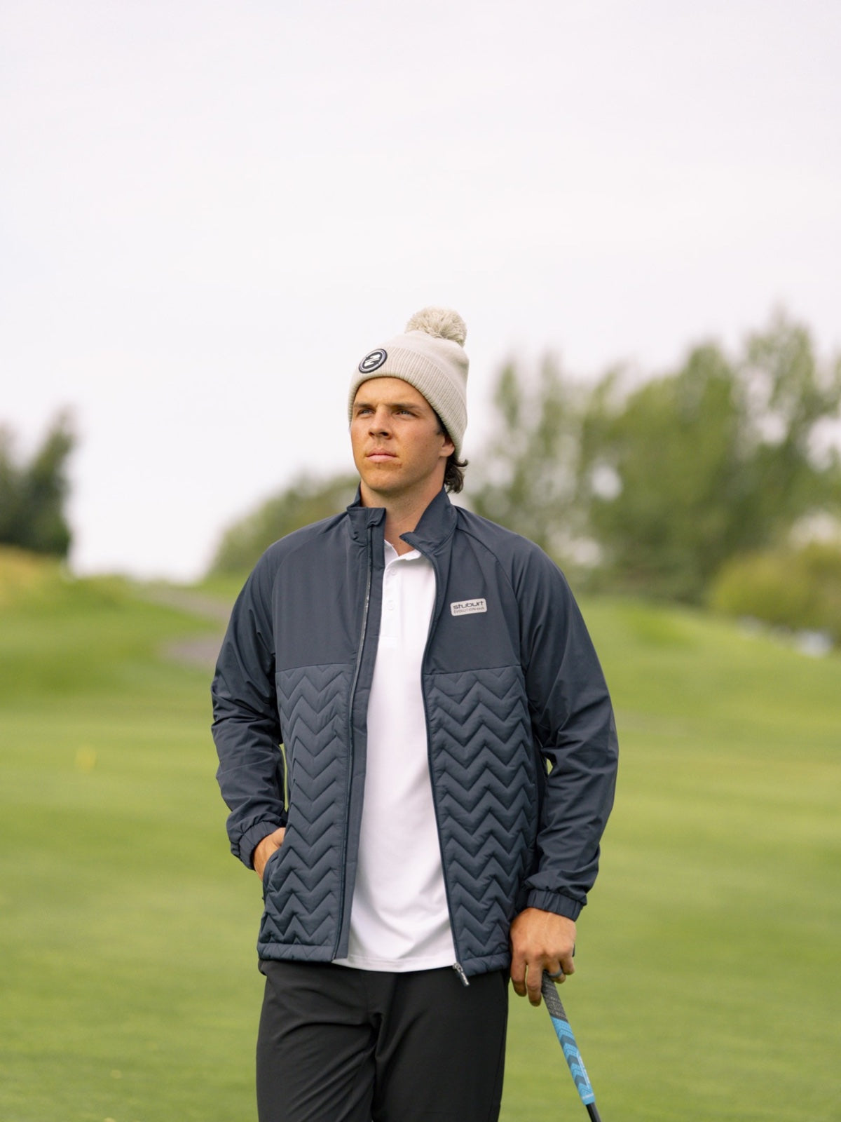 Golfer in a navy chevron-quilted Stuburt jacket over a white polo, on the course