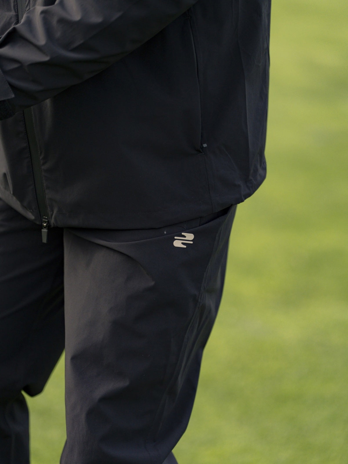Black Stuburt waterproof jacket worn with matching waterproof trousers on the course